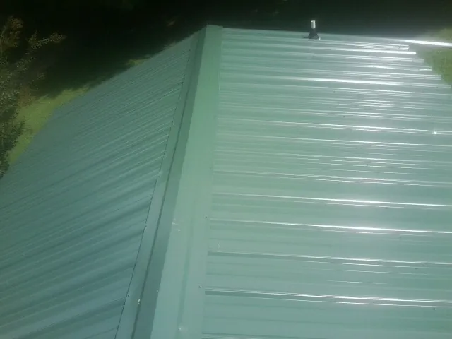New green metal panels meeting at the ridge of a roof — Flat Roof Repair work by our crew in East Elmhurst
