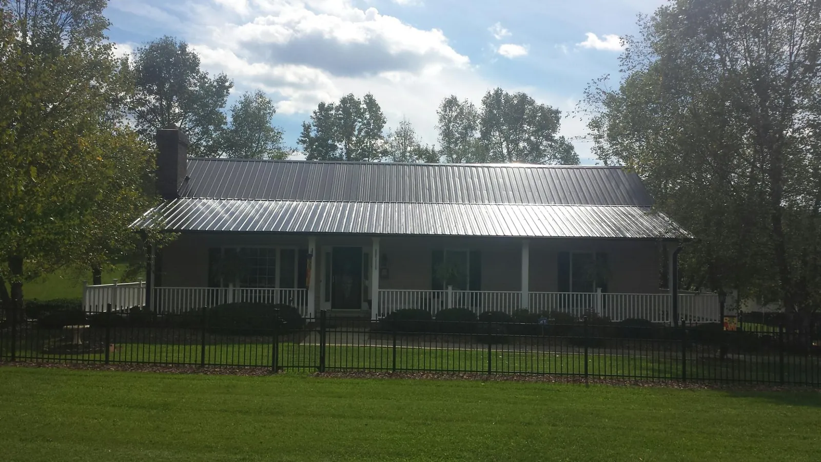 Gray metal roof on a brick ranch with a full width front porch — Gutter Guard Installation work by our crew in East Elmhurst