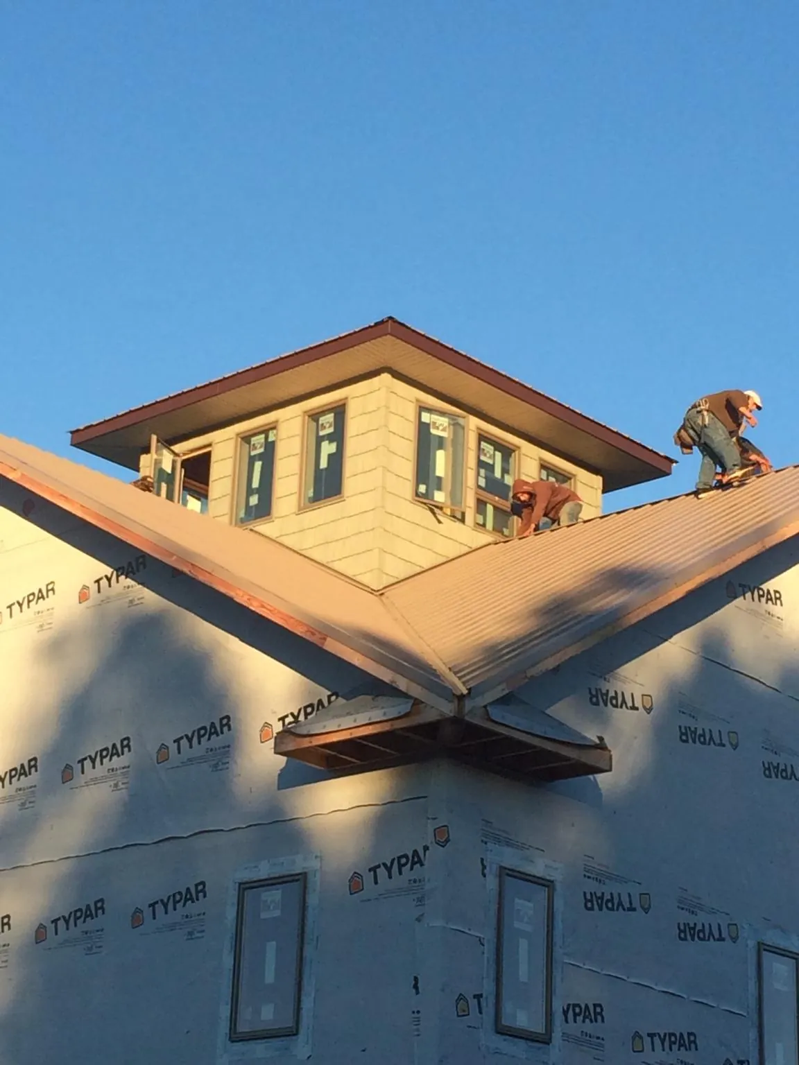 Roofers working around a rooftop cupola on a new metal roof at sunset — Roof Waterproofing in East Elmhurst by Roofing Brothers